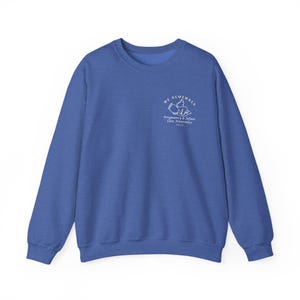May include: A royal blue sweatshirt with a crew neck. The front left chest features white text and a graphic that reads "WE REMEMBER" above "Pregnancy & Infant Loss Awareness 2023". The sweatshirt is made of a soft material.
