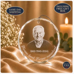 May include: A circular glass ornament featuring a laser-etched portrait of an older man. The text DAD (1945-2024) and Forever loved. Forever remembered. is engraved below the portrait. The ornament includes a metal hanging loop.