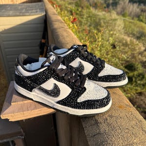 K&ouml;nnte beinhalten: Ein Paar schwarz-wei&szlig;e Nike Dunk Low Sneaker. Die Schuhe haben ein schwarz-wei&szlig;es Farbschema mit einer juwelenartigen Textur auf den schwarzen Paneelen und einem wei&szlig;en Swoosh. Die Schn&uuml;rsenkel sind schwarz.