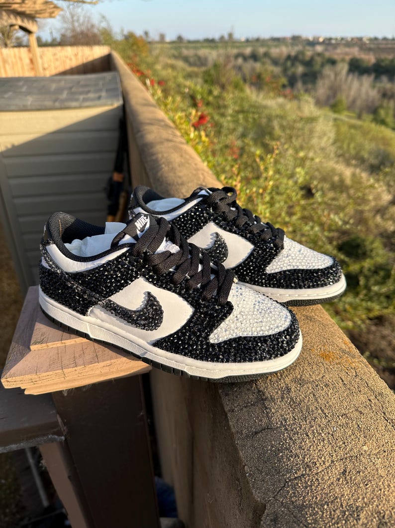 K&ouml;nnte beinhalten: Ein Paar schwarz-wei&szlig;e Nike Dunk Low Sneaker. Die Schuhe haben ein schwarz-wei&szlig;es Farbschema mit einer juwelenartigen Textur auf den schwarzen Paneelen und einem wei&szlig;en Swoosh. Die Schn&uuml;rsenkel sind schwarz.