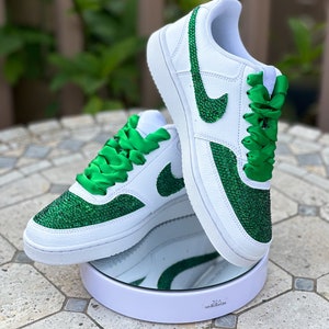 May include: White leather sneakers with green glitter and green satin laces. The Nike swoosh is also covered in green glitter.