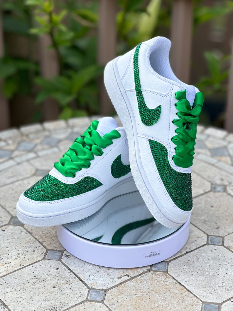 May include: White leather sneakers with green glitter and green satin laces. The Nike swoosh is also covered in green glitter.