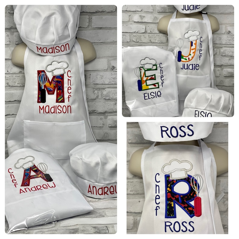 K&ouml;nnte beinhalten: Wei&szlig;e Kinder-Kochsch&uuml;rzen und -m&uuml;tzen mit personalisierten Namen. Jede Sch&uuml;rze hat einen gro&szlig;en Anfangsbuchstaben mit Kochm&uuml;tzen- und Schneebesen-Design. Namen: Madison, Andrew, Judie, Elsie und Ross.