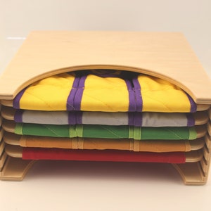 Puede incluir: Caja de almacenamiento de madera con tapa curva y seis compartimentos. Cada compartimento contiene un cuadrado de tela de color diferente con ribete morado y verde.