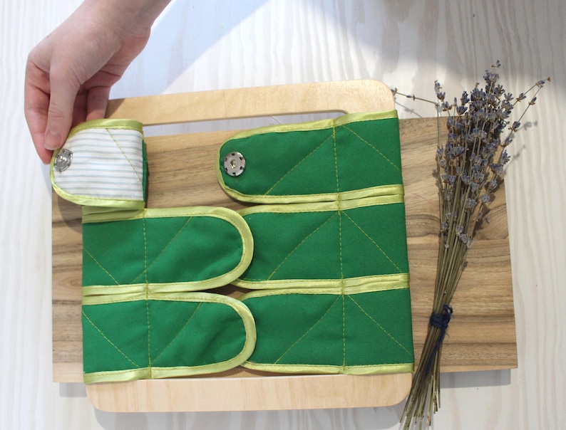 Puede incluir: Un marco de madera con tiras de tela verde con ribetes amarillos y cierres de bot&oacute;n. Las tiras de tela est&aacute;n cosidas con un patr&oacute;n de diamante. El marco est&aacute; sobre una superficie de madera con un ramo de lavanda seca.