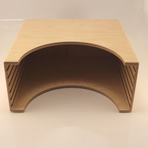 Puede incluir: Una caja de almacenamiento de madera con una abertura curva y una serie de listones en los lados. La caja es de madera marr&oacute;n claro y est&aacute; vac&iacute;a.