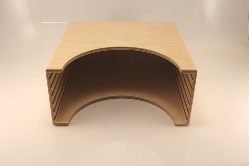 Puede incluir: Una caja de almacenamiento de madera con una abertura curva y una serie de listones en los lados. La caja es de madera marr&oacute;n claro y est&aacute; vac&iacute;a.