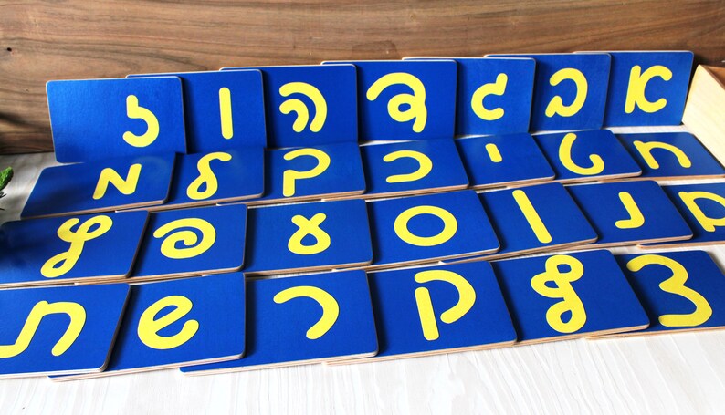 May include: A set of blue and yellow alphabet letter tiles. The tiles are made of wood and have a yellow letter on a blue background.