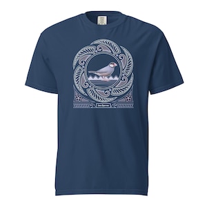 May include: A navy blue t-shirt featuring a white and light blue design of a Java Sparrow bird within a circular frame. The frame is adorned with a Polynesian-inspired pattern. The text "Java Sparrow" is printed beneath the design.