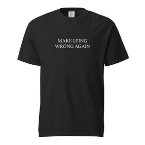 Może przedstawiać: Czarny t-shirt z krótkim rękawem z białym napisem "MAKE LYING WRONG AGAIN" pośrodku z przodu. Koszulka ma klasyczny okrągły dekolt i luźny krój, odpowiedni do noszenia na co dzień.