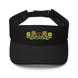 May include: Black visor with embroidered floral and peace sign design. The visor features a curved brim and an adjustable strap. The embroidered design includes yellow and brown flowers with blue centers, green leaves, and a brown peace symbol.