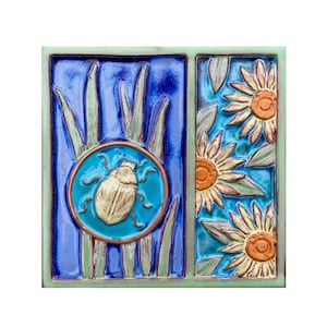 May include: A ceramic tile with a blue and green background. The tile features a yellow beetle in a circle and a pattern of sunflowers.