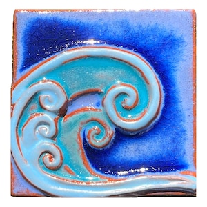Puede incluir: Un azulejo de cerámica azul y turquesa con un diseño en relieve de una ola estilizada. La ola está formada por espirales y tiene un esmalte azul claro.