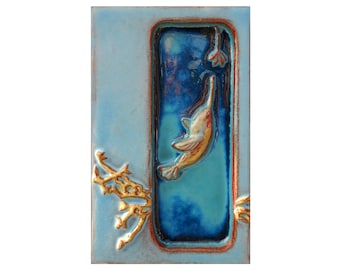 May include: A blue ceramic tile with a raised image of a bird in flight. The bird is yellow and orange with a blue background. The tile has a gold border.