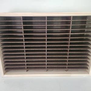 May include: A wooden storage box with multiple horizontal shelves. The shelves are made of a brown material and are evenly spaced. The box has a light-colored wooden frame.