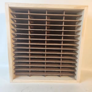 May include: A wooden box with a grid of horizontal and vertical brown slats. The frame is made of light-colored wood. The slats create a series of small rectangular compartments.