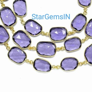 May include: A strand of purple faceted gemstone beads strung on a gold chain. The beads are rectangular in shape and have a smooth, polished finish.