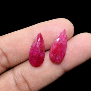 May include: Two teardrop-shaped pink gemstones with a faceted cut.