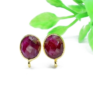 Puede incluir: Un par de pendientes de tono dorado con acentos de piedras preciosas rojas. Los pendientes tienen un diseño simple y elegante y son perfectos para el uso diario.