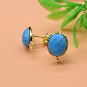 May include: A pair of gold earrings with blue gemstone accents. The earrings have a simple design and are perfect for everyday wear.