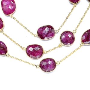 Puede incluir: Un collar de cadena de oro con múltiples hebras presenta grandes piedras preciosas ovaladas de rubí facetadas. El collar es una pieza llamativa con un diseño audaz y elegante.