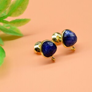 May include: A pair of gold stud earrings with blue gemstone accents.