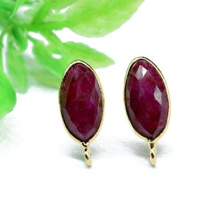 Pode incluir: Um par de brincos de ouro com pedras preciosas vermelhas de forma oval. Os brincos têm um design simples e são perfeitos para o uso diário.