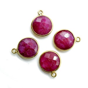 Op de afbeelding: Vier ronde hangers van robijnrode edelstenen met gouden instellingen. Elke hanger heeft een lus om aan een ketting of koord te bevestigen.