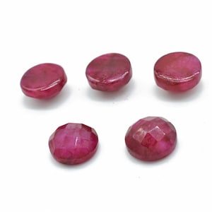 Op de afbeelding: Zes ronde, gefacetteerde robijn edelstenen in verschillende tinten roze. De edelstenen zijn ongeveer 10 mm in diameter.