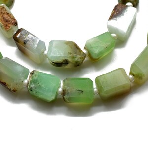 May include: A necklace featuring faceted, rectangular green and white gemstones with brown accents. Small, round, white pearls are interspersed between the stones. The necklace is displayed against a white background.