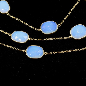 May include: A gold chain necklace with multiple strands featuring oval-shaped blue opal stones.