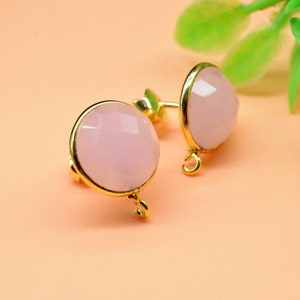 May include: A pair of gold earrings with pink gemstone accents. The earrings have a simple design and are perfect for everyday wear.