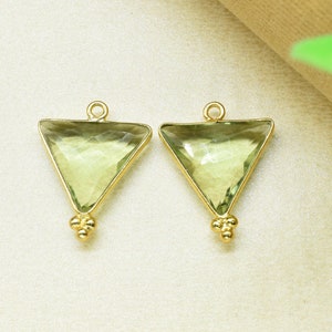 May include: Two gold triangle shaped pendants with light green gemstone accents. The pendants have a small gold ball at the bottom.