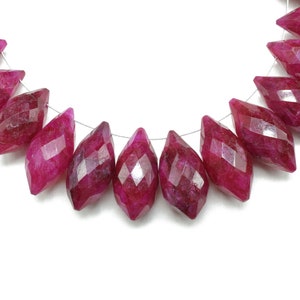 May include: A strand of faceted ruby beads, each bead is a deep pink color and has a pointed, teardrop shape.
