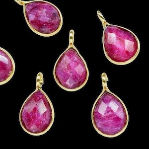 Pode incluir: Sete pingentes de rubi em forma de lágrima com engastes de ouro. As pedras preciosas são de cor rosa intenso e têm um acabamento facetado.