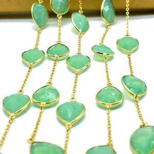 May include: A gold chain necklace with green gemstone beads. The beads are faceted and have a teardrop shape.