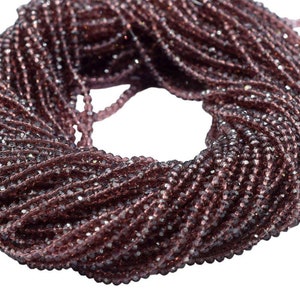May include: A strand of dark purple faceted glass beads. The beads are small and round, and they are strung together on a clear thread.