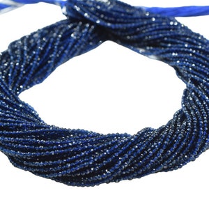 May include: A twisted strand of small, dark blue beads. The beads are tightly strung together, forming a thick, rope-like shape. A blue ribbon is tied at the top. The beads have a slight sparkle, suggesting they may be gemstones.