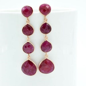Puede incluir: Un par de pendientes largos y colgantes con cuatro piedras preciosas facetadas en forma de lágrima, de color rosa, en cada pendiente.