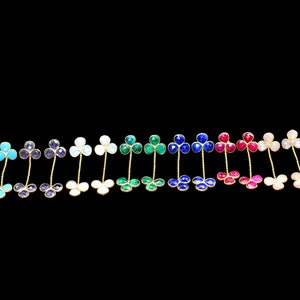 May include: A set of 16 pairs of dangle earrings featuring a clover design with different colored gemstones. The earrings are made of gold metal and have a delicate chain.