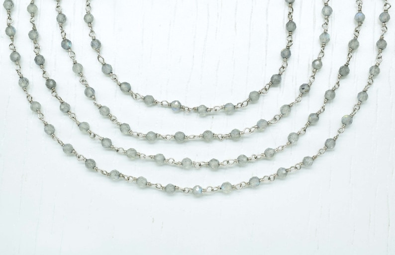 May include: A layered necklace with five strands of silver chain and grey gemstone beads.