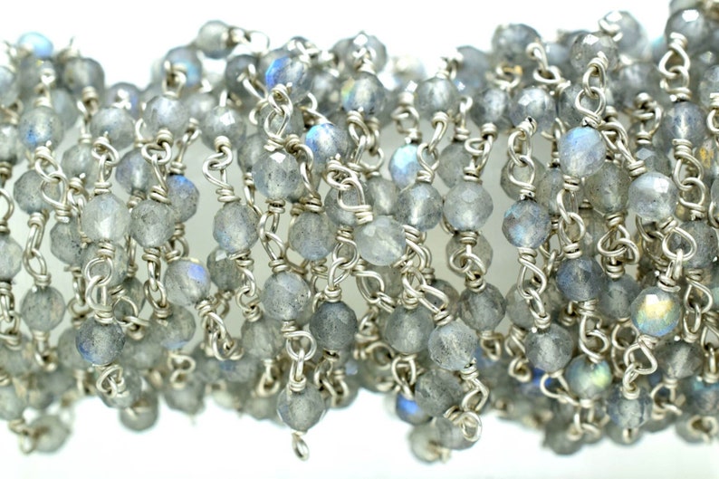 May include: A silver chain with faceted labradorite beads. The chain is made of small, linked silver rings. The beads are a light gray color with iridescent blue and green flashes.