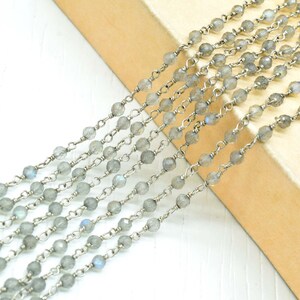 May include: A strand of silver chain with faceted, light gray labradorite beads. The chain is made of small, delicate links.