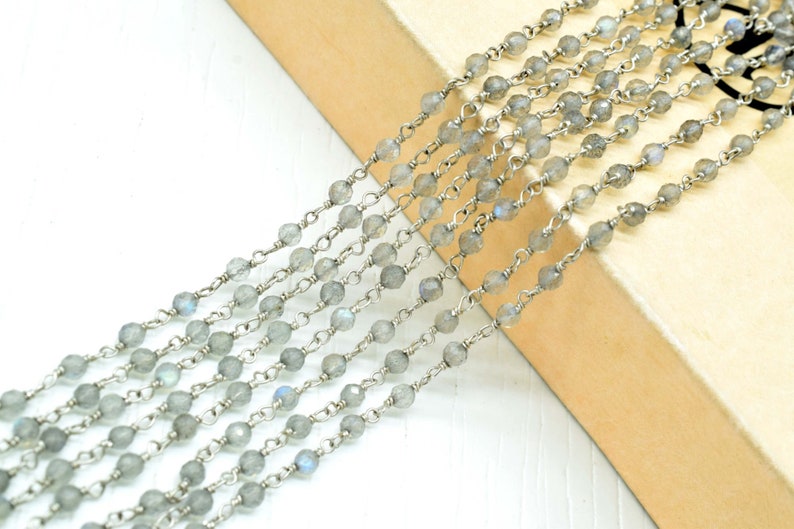 May include: A strand of silver chain with faceted, light gray labradorite beads. The chain is made of small, delicate links.