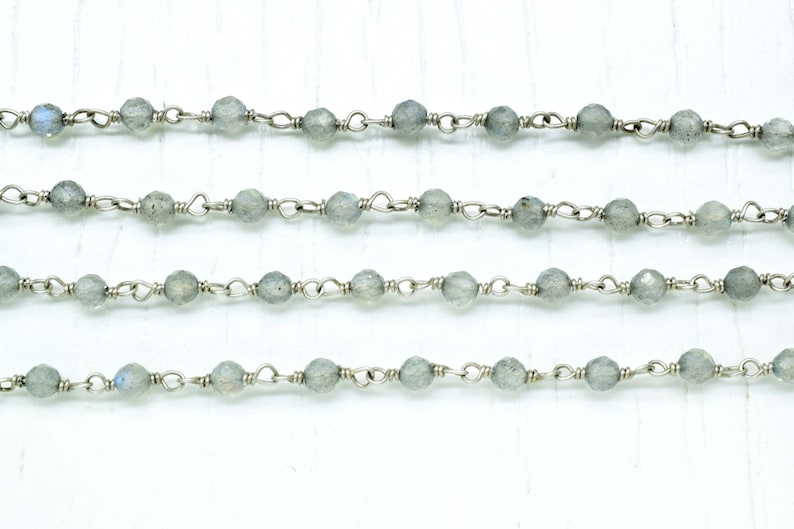 May include: A silver chain with grey gemstone beads. The chain is made of small, delicate links and the beads are round and smooth.