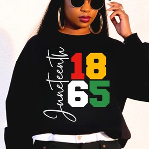May include: Black sweatshirt with a white graphic that says "Juneteenth 1865" in red, yellow, white, and green.