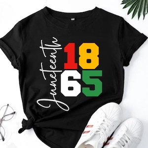 May include: Black t-shirt with white text that says "Juneteenth 1865". The numbers are in red, yellow, white, and green squares.