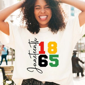 May include: A white t-shirt with the text "Juneteenth" and the numbers "1865" in red, yellow, black, and green.