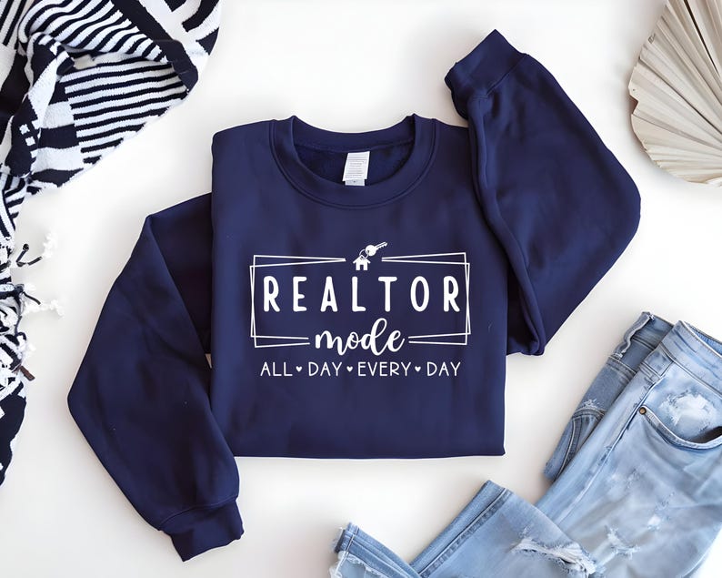 May include: Navy blue sweatshirt with white text that reads "Realtor mode - All Day Every Day" with a house and key graphic.