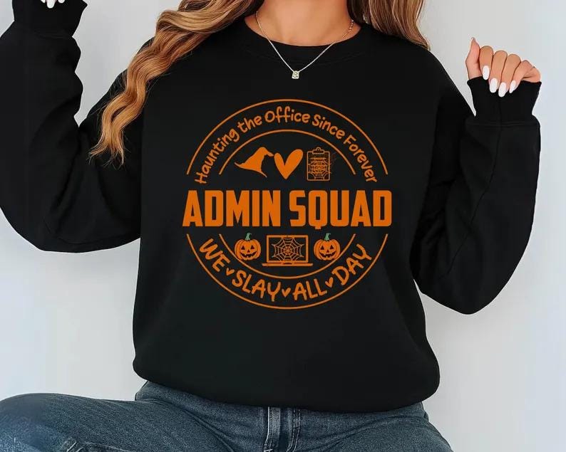 May include: Black sweatshirt with an orange graphic that reads "ADMIN SQUAD" in a circular design with Halloween-themed icons and the phrases "Haunting the Office Since Forever" and "We Slay All Day."